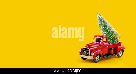 Camion de jouet rétro rouge avec arbre de Noël sur la caisse de camion sur fond jaune. Livraison, noël, concept du nouvel an. Voiture modèle vintage jouet avec Christm Banque D'Images