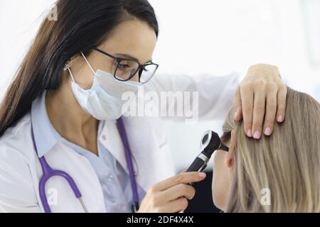 Otorhinolaryngologiste regardant les patients femelles oreille avec otoscope en clinique Banque D'Images