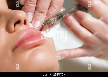 procédure de correction de la forme des lèvres dans un salon de cosmologie. Le spécialiste effectue une injection sur les lèvres du patient. Augmentation des lèvres. Banque D'Images