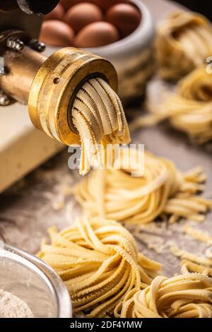 Production d'une pâte à pâtes fraîche pour les nids de fettuccine quittant la machine à pâtes. Banque D'Images