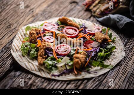 Ouvrir la tortilla avec des nuggets de poulet, des tomates cerises, du chou rouge, de la salade et des bandes de carottes. Banque D'Images