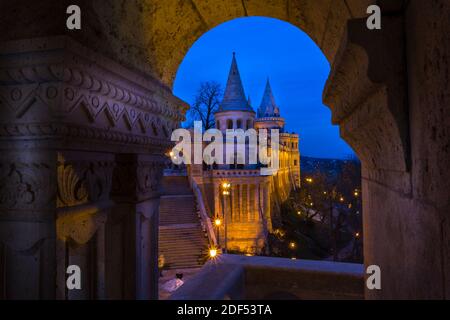 Vue sur le Bastion des pêcheurs à travers une arche sculptée au crépuscule, colline du château de Buda, Budapest, Hongrie, Europe Banque D'Images