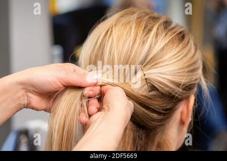 Gros plan des mains du coiffeur en braquant les cheveux du client dans le salon de beauté Banque D'Images