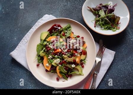 Salade saine persimmon, fromage bleu, épinards, arugula, feuilles de laitue sur plaque blanche Banque D'Images