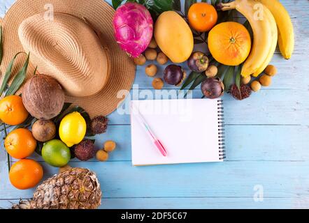 Fruits tropicaux et chapeau avec carnet avec espace de copie arrière-plan en bois sur le thème des voyages tropicaux Banque D'Images