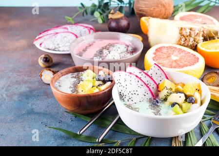 Table de petit-déjeuner avec du yogourt l'açaï bols et des fruits tropicaux sur un fond noir en gris avec des feuilles d'eucalyptus, Banque D'Images