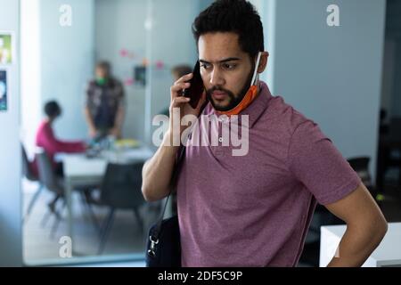Homme de course mixte portant un masque facial dans un bureau Banque D'Images