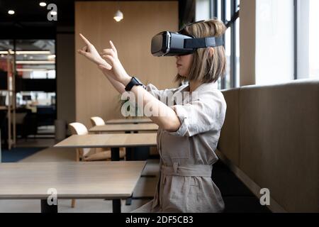 Femme d'affaires asiatique portant un casque de réalité virtuelle dans un bureau créatif Banque D'Images