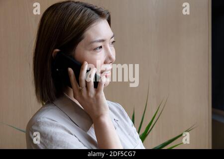Femme d'affaires asiatique parlant sur un smartphone dans un bureau créatif Banque D'Images
