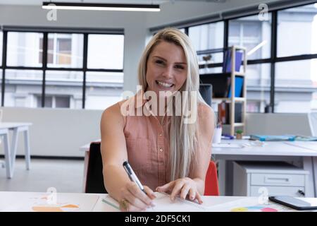 Portrait d'une femme blonde blanche souriante travaillant dans un bureau moderne Banque D'Images