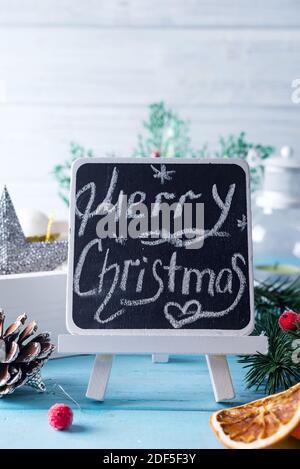 Tableau noir avec légende « Joyeux Noël ! » et décoration de noël sur fond bleu Banque D'Images