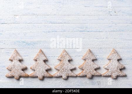 Biscuits au pain d'épice aux flocons d'avoine en forme d'arbre de Noël saupoudrés de sucre sur fond bleu clair, vue du dessus, espace libre Banque D'Images
