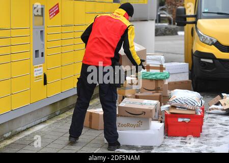 Munich, Allemagne. 03ème décembre 2020. Les volumes de colis et le commerce en ligne sont en plein essor en période de pandémie du virus corona. Le livreur de colis DHL, transporteur de colis, au travail, met le colis dans un compartiment d'une station d'emballage. Décharge sa voiture, son autobus postal, DHL, colis, colis, service de colis, livraison, livraison, déchargement, expédition, transporteur, camion à main. | utilisation dans le monde crédit: dpa/Alay Live News Banque D'Images