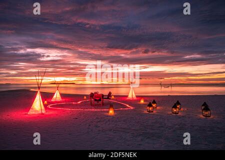 Une destination exceptionnelle avec des bougies et un cœur en forme de cœur et des lumières LED sous un ciel magnifique au coucher du soleil. Couple romantique amour lune de miel concept près de la mer Banque D'Images