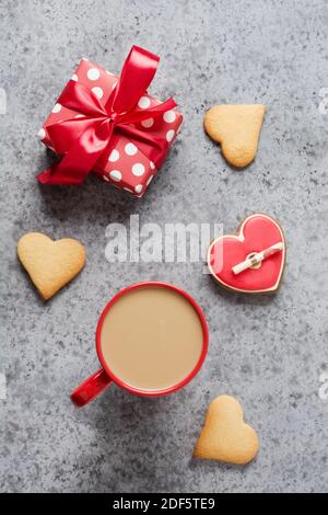 Tasse de café et cadeau, petits gâteaux faits maison avec lettre d'amour sur table grise. Carte de voeux pour la Saint-Valentin. Vue de dessus. Format vertical. Banque D'Images