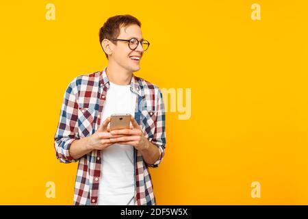 gai homme a reçu un message sur le téléphone, sur fond jaune, le gars avec le téléphone dans ses mains Banque D'Images