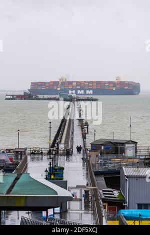 Southend Pier, Southend on Sea, Essex, Royaume-Uni. 3 décembre 2020. Le HMM Rotterdam est un navire conteneur de classe Algeciras, un groupe de douze navires cargo qui peuvent également transporter le plus grand nombre de conteneurs par n'importe quel navire dans le monde, à près de 24,000 conteneurs. Le HMM Rotterdam de 400 m de long et de 232 000 tonnes est entré en service en juin 2020 et effectuera des trajets réguliers entre l'Asie et l'Europe. Il a quitté le port de la DP World London Gateway dans la Tamise à Stanford le Hope, dans l'Essex, en direction de la mer du Nord et est vu s'élevant au-dessus de Southend Pier Banque D'Images