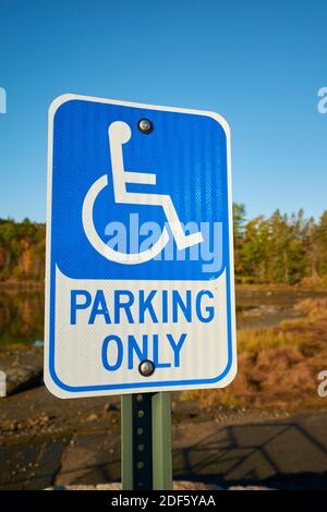 Un panneau bleu pour les personnes à mobilité réduite se trouve dans un parking de la guerre de Surry, dans le Maine. Dans la nature, avec les couleurs d'automne, d'automne. Banque D'Images