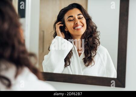 Belle femme du Moyen-Orient avec les yeux fermés debout devant d'un miroir Banque D'Images