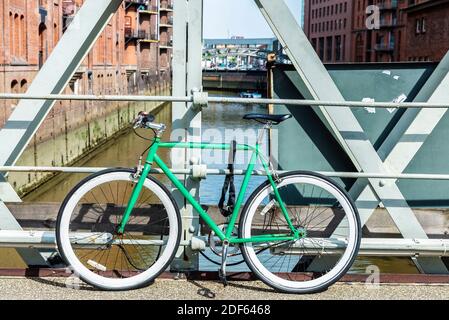 Vieux vélo vert vintage stationné sur un pont sur un canal à Hambourg, Allemagne Banque D'Images