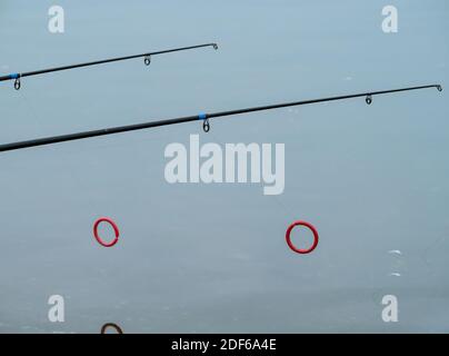 Ligne de pêche de monofilament sur un anneau de canne de pêche contre l'eau bleue. Banque D'Images