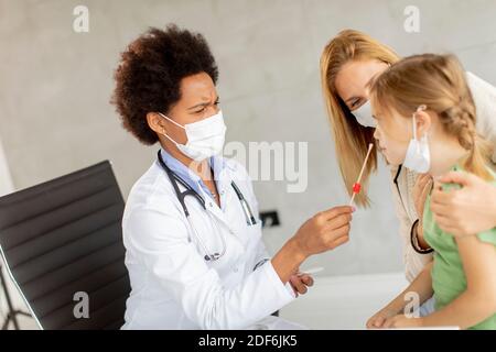 Mère avec sa petite fille à l'examen pédiatre et Avoir un test de diagnostic PCR par une femme médecin afro-américaine Banque D'Images