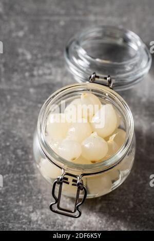 Petits oignons marinés dans un pot sur une table de cuisine. Banque D'Images