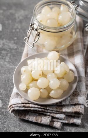 Petits oignons marinés dans un pot sur une table de cuisine. Banque D'Images