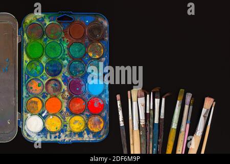 Peinture aquarelle et pinceaux sur fond noir. Banque D'Images