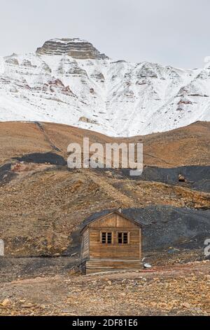 Ancienne hutte en bois et ses adits / mine de charbon entrées sur la pente de montagne à Pyramiden, site abandonné de l'extraction de charbon soviétique sur Svalbard / Spitsbergen Banque D'Images