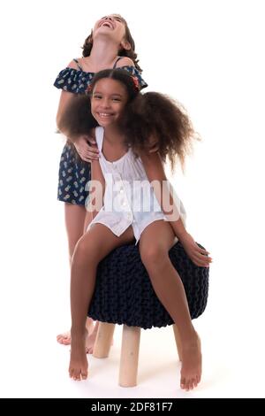 Deux petites filles amicales riant , amis ou sœurs - hispanique et afro-américaine - isolé sur blanc Banque D'Images