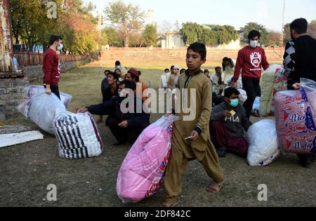 Les volontaires de Practice Abonté distribuent des couvertures/couettes parmi les travailleurs sans abri lors de la cérémonie de distribution qui s'est tenue au terrain de cricket du G-9/1 à Islamabad, le jeudi 3 décembre 2020. Banque D'Images