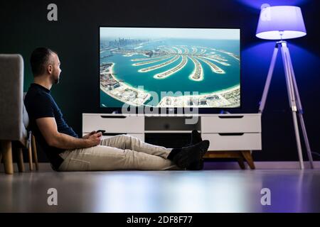 Diffusion sur le téléviseur connecté à partir de la tablette. Homme regardant un film Banque D'Images