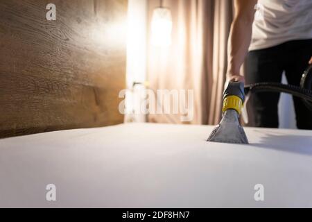 Man nettoie le matelas de la poussière et de la saleté avec l'aspirateur à laver. Processus de nettoyage du lit Banque D'Images