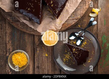 Gâteau au chocolat avec glaçage et zeste de citron sur fond de bois. Banque D'Images