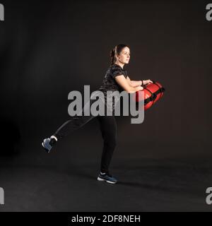 Fitness avec Aqua Bag, étire ses bras et tire sa jambe dans différentes directions. Engagé dans le sport sur un fond noir regarde drôle à la ca Banque D'Images