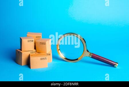 Pile de boîtes et loupe. Vérification des achats. Surveillance et vérification des marchandises, certification des importations. Recherche de marchandises et de composants. C'est Banque D'Images