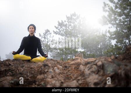 Femme méditant et pratiquant le yoga au sommet de la montagne Banque D'Images