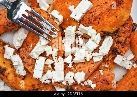 Fourchette sur la courge butternut grillée orange vif et la feta blanche fromage Banque D'Images