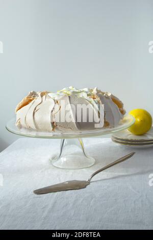 Gâteau à la meringue maison Pavlova avec crème fouettée et citron support à gâteau en verre sur fond clair Banque D'Images