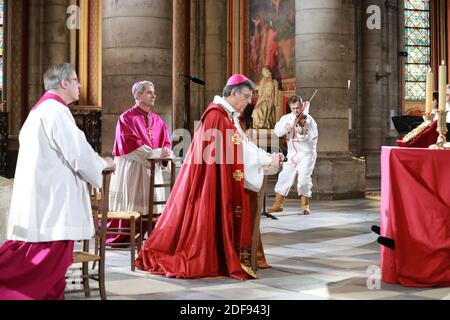 (À partir de L) le recteur de la cathédrale notre-Dame de Paris, Patrick Chauvet, l'évêque auxiliaire de Paris, Denis Jachiet et l'archevêque de Paris, Michel Aupetit assistent à une cérémonie de méditation pour célébrer le Vendredi Saint alors que Renaud Capucon, violoniste, joue dans une partie sécurisée de la cathédrale notre-Dame de Paris le 10 avril 2020, À Paris, le 25e jour d'un verrouillage strict visant à freiner la propagation de la pandémie COVID-19, causée par le nouveau coronavirus. - notre-Dame, qui fait partie d'un site du patrimoine mondial de l'UNESCO sur les rives de la Seine, a été ravagée par le feu d'avril 15 -- perdant sa flèche gothique, son toit et de nombreux preci Banque D'Images