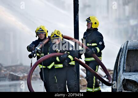 Londres, Angleterre - le 9 août 2011 : pompiers à Londres à la suite des émeutes à Croydon tirant un tuyau à une nouvelle position trois pompiers s'en sont éredépeuplés Banque D'Images