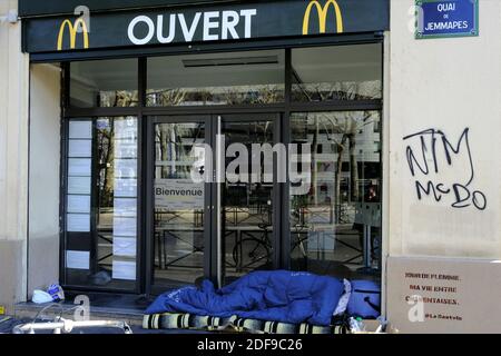 Un homme sans abri qui dormait à l'entrée du mac mac Mcdonalda à Paris pendant la maladie du coronavirus (COVID-19). Après l'annonce par le président français Emmanuel Macron des règles strictes de confinement à domicile des Français en raison d'une épidémie de coronavirus (COVID-19) le 18 mars 2020 à Paris, France. Les Français devront rester chez eux, la France a fermé toutes les écoles, théâtres, cinémas et toute une gamme de magasins, avec seulement ceux qui vendent de la nourriture et d'autres articles essentiels autorisés à rester ouverts. Sous peine de sanctions, interdire toutes les sorties, sauf essentielles, pour tenter de freiner la co Banque D'Images