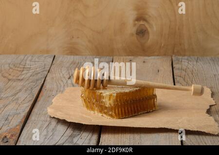 Miel en nid d'abeille et cuillère sur papier d'emballage sur une table en bois. Mise au point sélective. Banque D'Images