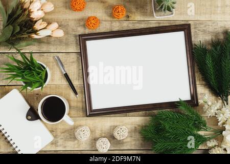 Cadre en bois, agenda et café avec décoration de fleurs sur fond de bois. Posé plat rustique avec nostalgie. Banque D'Images