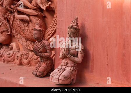 Statues à l'extérieur du temple rouge en Thaïlande, Ko Samui, priant ou méditant Banque D'Images