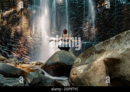Femme faisant du yoga pose devant une cascade à Kionsom Park, Sabah, Malaisie. Banque D'Images