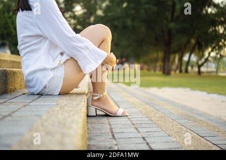 Femme assise sur des escaliers en béton dans le parc. Banque D'Images