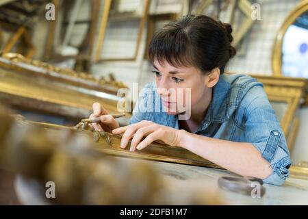 Artisan femelle travaille sur un grand cadre photo en bois Banque D'Images