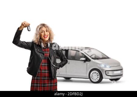 Jeune femme dans une veste en cuir tenant une clé de une petite voiture urbaine isolée sur fond blanc Banque D'Images